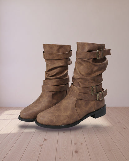 Brown buckled mid-calf boots on a light wood floor